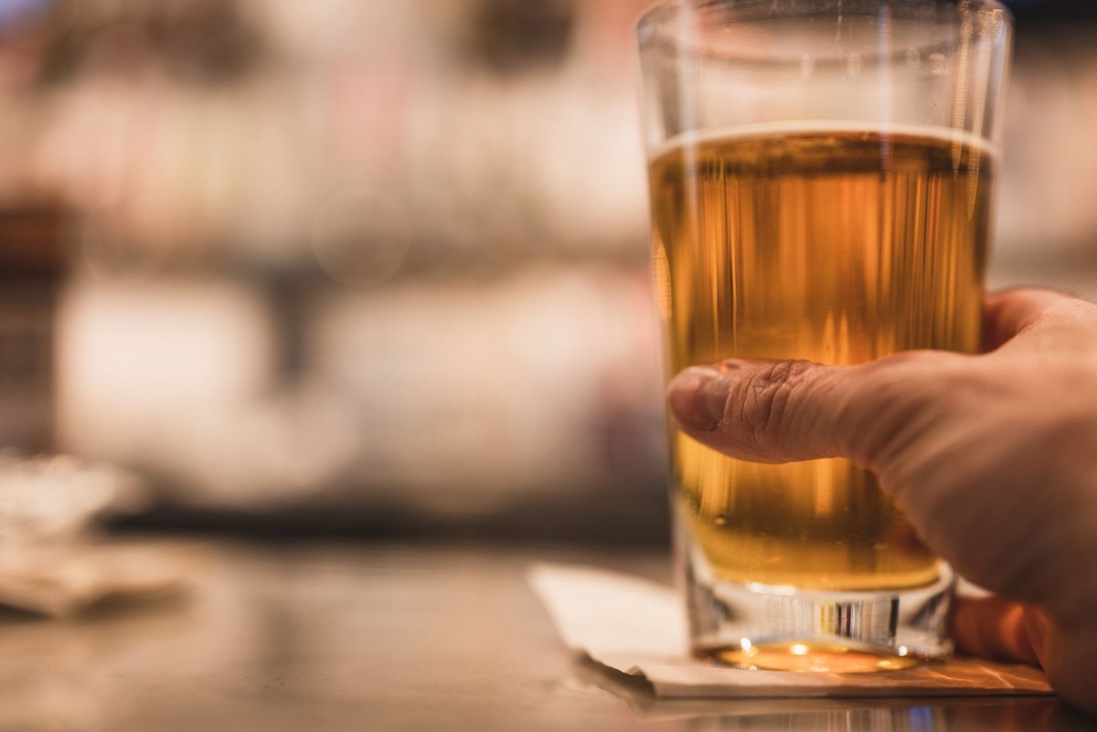 Een glas alcohol naast een illustratie van de lever.