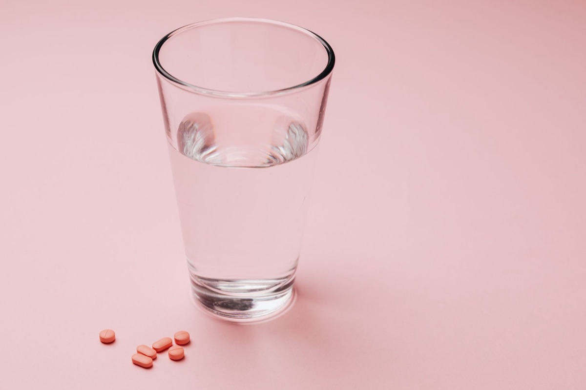 A glass of water and a pill organizer on a bright kitchen counter.