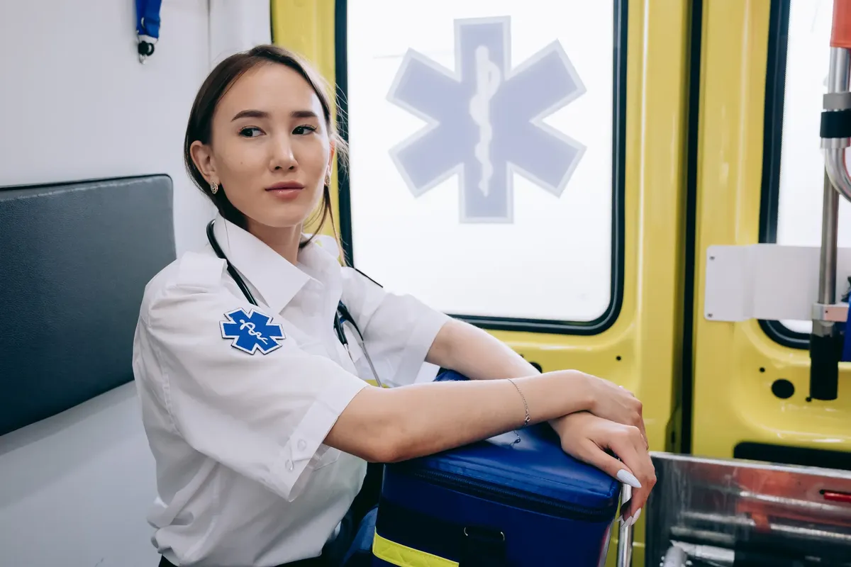 Asian woman paramedic inside an ambulance ready for emergency response.